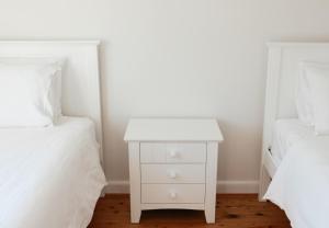 a white night stand next to two beds at Mystics Beach Bungalows in Minnamurra
