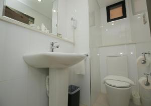 a white bathroom with a sink and a toilet at Ela Beach Hotel in Port Moresby
