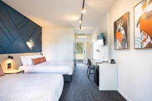 a hotel room with two beds and a desk at Nightcap at Sandown Park Hotel in Noble Park