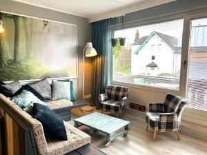 salon z kanapą, krzesłami i oknem w obiekcie Poppenberg Lodge w mieście Winterberg