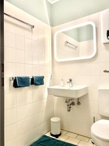 ein weißes Badezimmer mit einem Waschbecken und einem Spiegel in der Unterkunft Poppenberg Lodge in Winterberg
