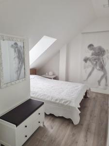 Un dormitorio con una cama blanca y una pared con cuadros. en Gallery Balta Apartments, en Kaunas