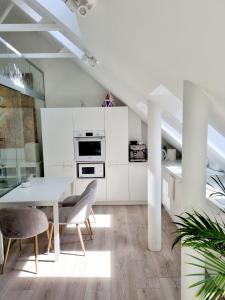 a white kitchen with a dining table and chairs at Gallery Balta Apartments in Kaunas