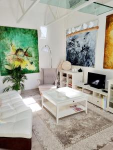 una sala de estar con muebles blancos y una pintura en la pared en Gallery Balta Apartments, en Kaunas