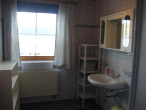 a bathroom with a sink and a mirror and a window at Sixenhof in Niederau