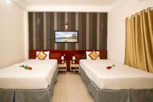 a hotel room with two beds and a tv at Ruby Hotel Côn Đảo in Ba Ria