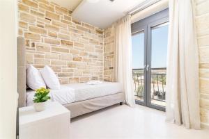 a brick walled bedroom with a bed and a window at Villa Eleana in Pitsidia +50 photos