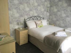 a bedroom with a bed and a nightstand with a bed sidx sidx sidx sidx at The Ramblers in Trusthorpe