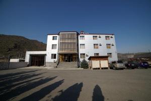 KapanSyunik Hotel的一座白色的大建筑,汽车停在停车场
