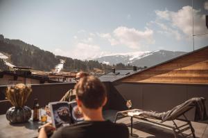 two people sitting on a balcony with a view of mountains at Mountainview Apartments in Westendorf