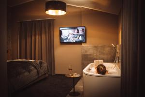 Mountainview Apartments في وستندورف: حمام مع حوض استحمام وتلفزيون على الحائط