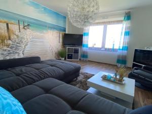 uma sala de estar com um sofá e uma pintura de uma praia em Ferienwohnung PuraVida Ostsee 5B em Bastorf