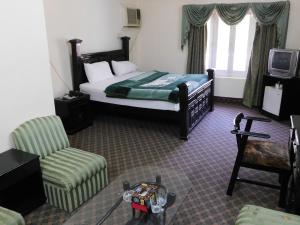 a hotel room with a bed and a chair at The City Lodge in Islamabad