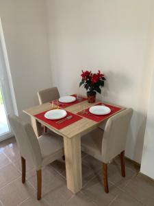 a wooden table with chairs and plates and a plant at Apartman Zmaj in Srbobran