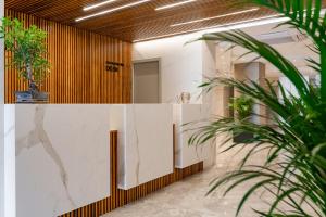 a lobby with a white wall with potted plants at Bayview Hotel by ST Hotels in Il-Gżira