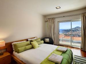 een slaapkamer met een groot bed met een groot raam bij The White House - By LovelyStay in Funchal +37 foto's