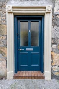 eine blaue Tür in einem Gebäude mit einer Steinmauer in der Unterkunft The Garden Cottage in Elgin
