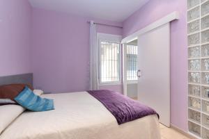 a bedroom with purple walls and a bed and a window at Hauzify I Apartament Subirats in Sant Feliu de Guíxols