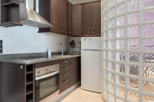 a kitchen with brown cabinets and a white refrigerator at Hauzify I Apartament Subirats in Sant Feliu de Guíxols
