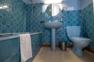 a blue tiled bathroom with a sink and a toilet at Au Bon Accueil in Juvigny-sous-Andaine