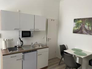 uma cozinha com armários brancos e uma mesa com cadeiras em Prime Host Smart Apartments em Karlsruhe
