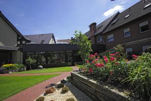 a house with a garden with flowers in the yard at Hotel Lindenkrug in Gütersloh