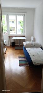 a bedroom with a bed and two windows and a wooden floor at Doubleroom close to lake in Citycenter in Zürich
