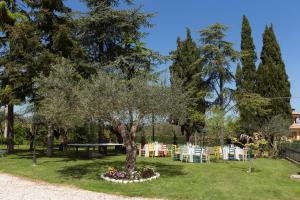 un parque con un árbol, mesas y sillas en Bed&Breakfast Il Frantoio, en Misano Adriatico