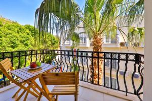 a balcony with a table and chairs and a palm tree at Bossa Nova Apart Hotel in Kaş