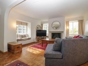 a living room with a couch and a tv at Burwell Cottage in Puncknowle