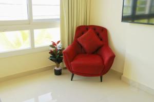 a red chair sitting in a room next to a window at ALmansor furnished Apartment 1 in Salalah