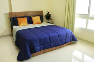 Una cama azul con almohadas naranjas en un dormitorio en ALmansor furnished Apartment 1 en Salalah