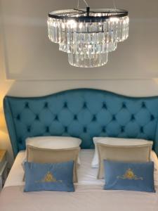 a bed with a blue headboard and a chandelier at Apartamenty Kamienica Arte 1 in Ustka