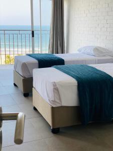 two beds in a room with a view of the ocean at 66Windemere self catering apartments in Durban