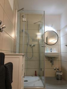 a shower with a glass door next to a sink at Pension Rehschopp in Ediger-Eller
