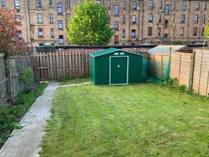 a green shed in a yard next to a fence at Dada Apartment in Glasgow