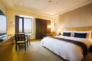 新竹市にあるアンバサダー ホテル シンチューの大きなベッドとデスクが備わるホテルルームです。