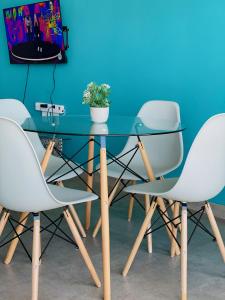 a glass table with three white chairs and a tv at 66Windemere self catering apartments in Durban