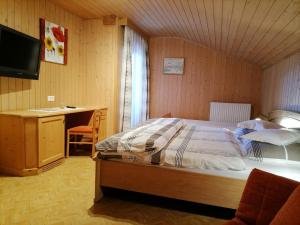 a bedroom with a bed and a desk and a television at Gasthaus Oberkirn in Schenna