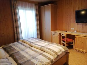 a bedroom with a bed and a desk and a window at Gasthaus Oberkirn in Schenna