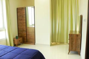 a bedroom with a blue bed and a mirror at ALmansor furnished apartment 3 in Salalah