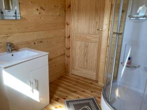 La salle de bains est pourvue d'un lavabo blanc et d'une douche. dans l'établissement Zarasaičio ežero sodyba, à Magučiai