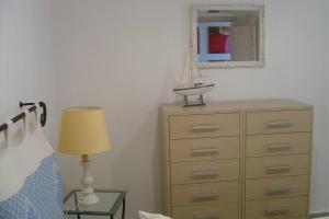 una camera da letto con cassettiera, lampada e specchio di Golfo di Marinella stupendo bilocale vista mare a Marinella