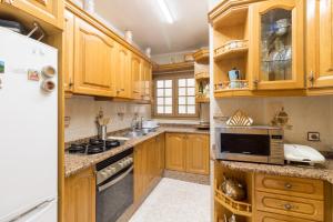 Una cocina con gabinetes de madera y un refrigerador blanco. en Apartment in front of the Beach, en Pineda de Mar