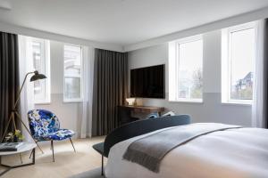 a bedroom with a bed, chair, desk and television at Kimpton De Witt Amsterdam, an IHG Hotel in Amsterdam