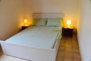 1 dormitorio con 1 cama blanca y 2 lámparas en La Casa del cancello di Borgo Carbone, en Locri