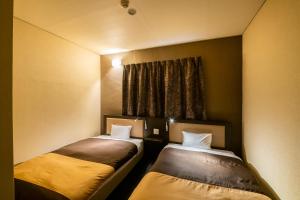 two beds sitting next to each other in a room at Kyoto Central Inn in Kyoto