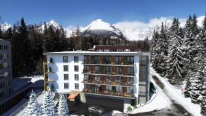 a hotel building with a snow covered mountain in the background at Armeria Residence Snow in Štrbské Pleso