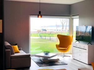 salon z telewizorem i żółtym krzesłem w obiekcie APARTAMENT ELEGANCE YELLOW w Nautica Resort w mieście Giżycko