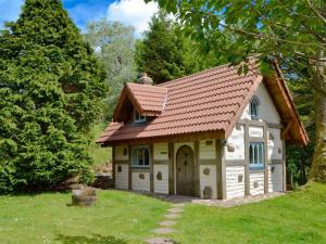 Snow Whites House - Farm Park Stay with Hot Tub في سوانسي: منزل صغير بسقف احمر في ساحة